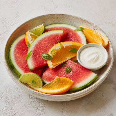 Watermelon half-moons and orange and lime wedges with their peel